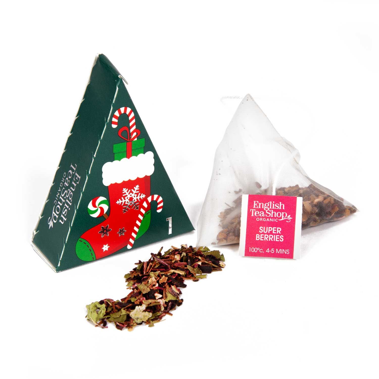 Driehoekige geschenkdoos met theezakje en losse thee. Opschrift: English Tea Shop, Super Berries. Rode achtergrond. Verpakking met kerstmotief.