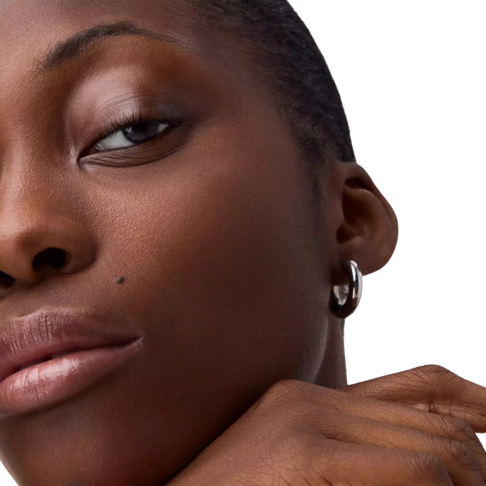 Gros plan d'un visage. Une femme à la peau foncée et aux boucles d'oreilles argentées.