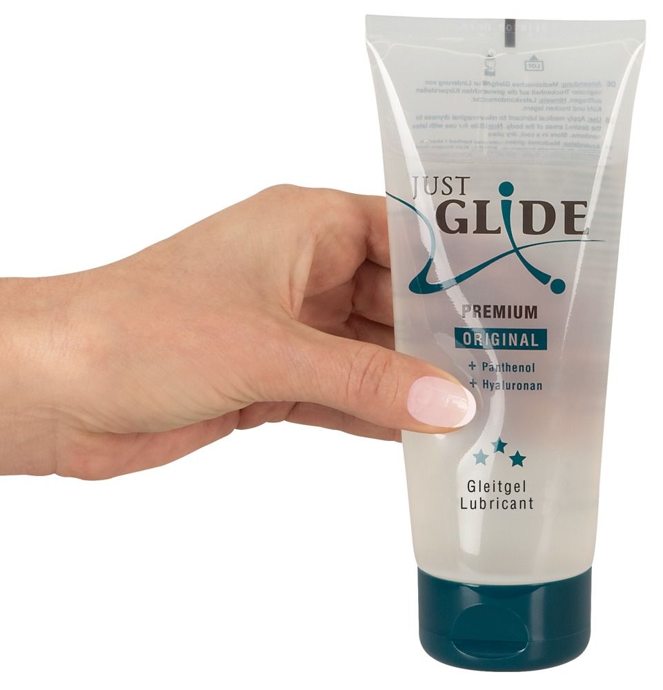 Main tenant un tube. Inscription : JUST GLIDE PREMIUM ORIGINAL. Contient du panthénol et de l'hyaluronan. Lubrifiant.
