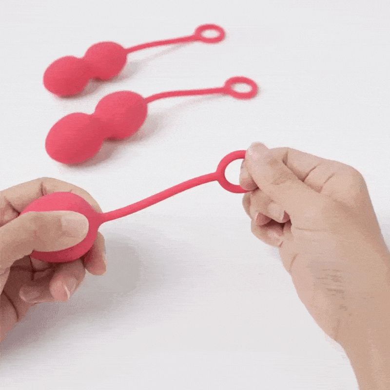 Trois boules roses avec des boucles. Une boule est tenue par une main.