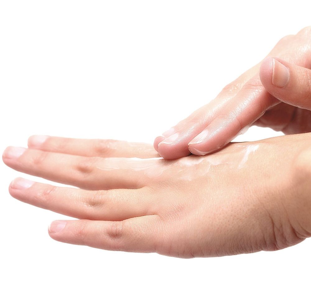 Handen, een handpalm met crème, een andere hand verdeelt de crème. Huidskleur, witte achtergrond.