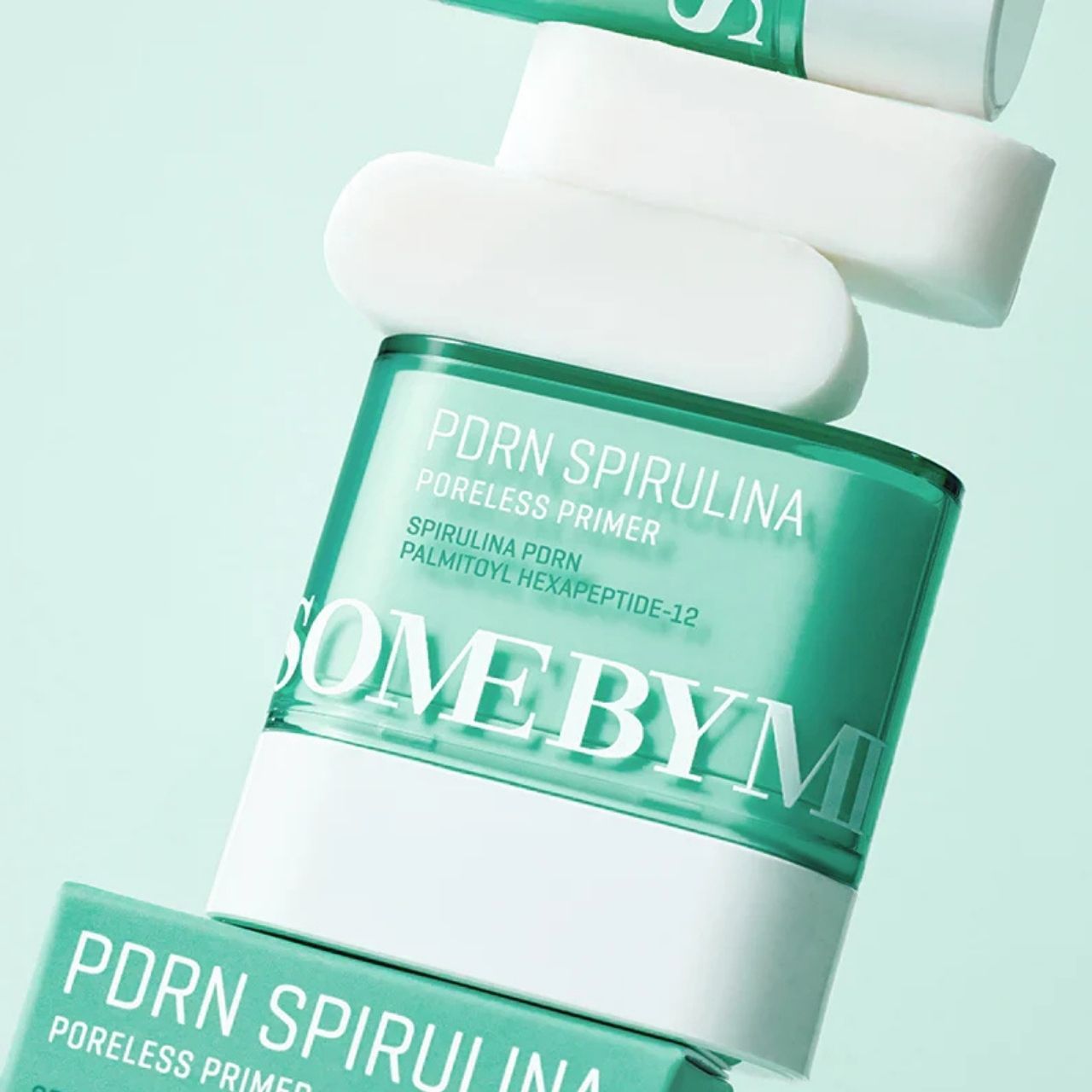 Plusieurs pots de SOME BY MI PDRN Spirulina Poreless Primer et des bâtonnets blancs, empilés et disposés en diagonale.