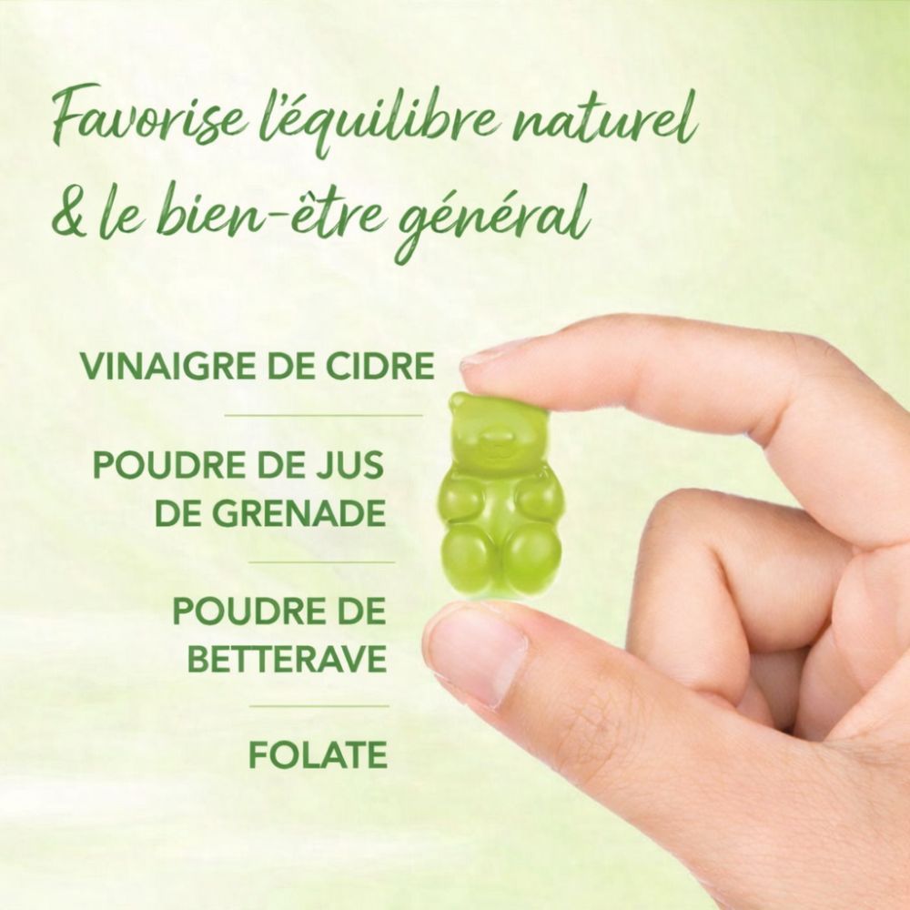 Main tenant un ourson gélifié vert. Texte : Vinaigre de cidre, Poudre de jus de grenade, Poudre de betterave, Folate.