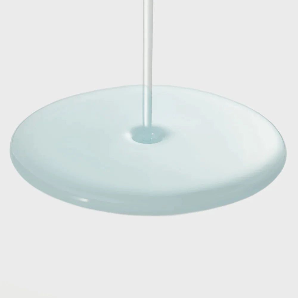 Druppel serum op een plat, rond oppervlak. Blauwe vloeistof. Pipet op de achtergrond.