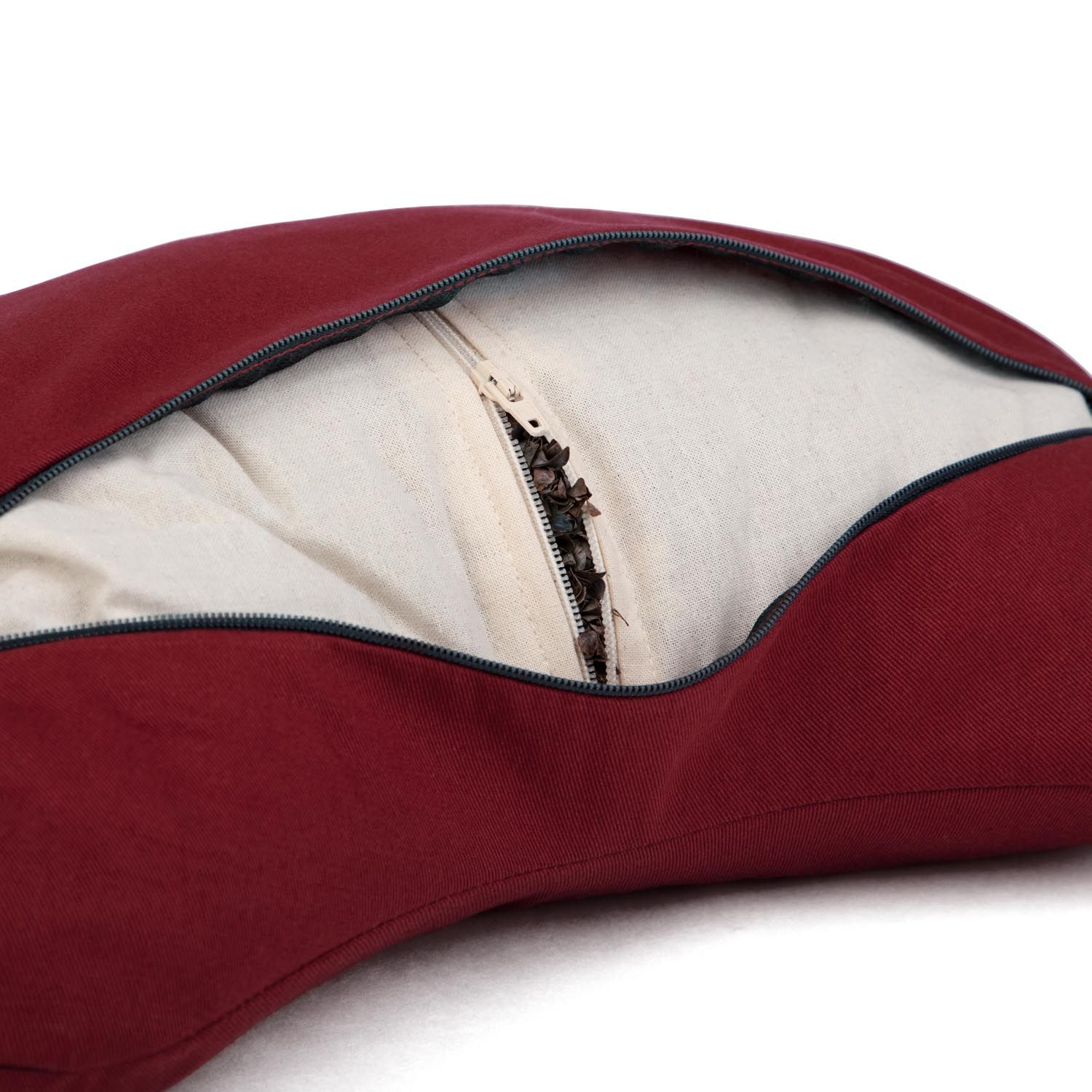 Gros plan de la fermeture éclair ouverte d'un coussin de méditation bordeaux en demi-lune, montrant le rembourrage.