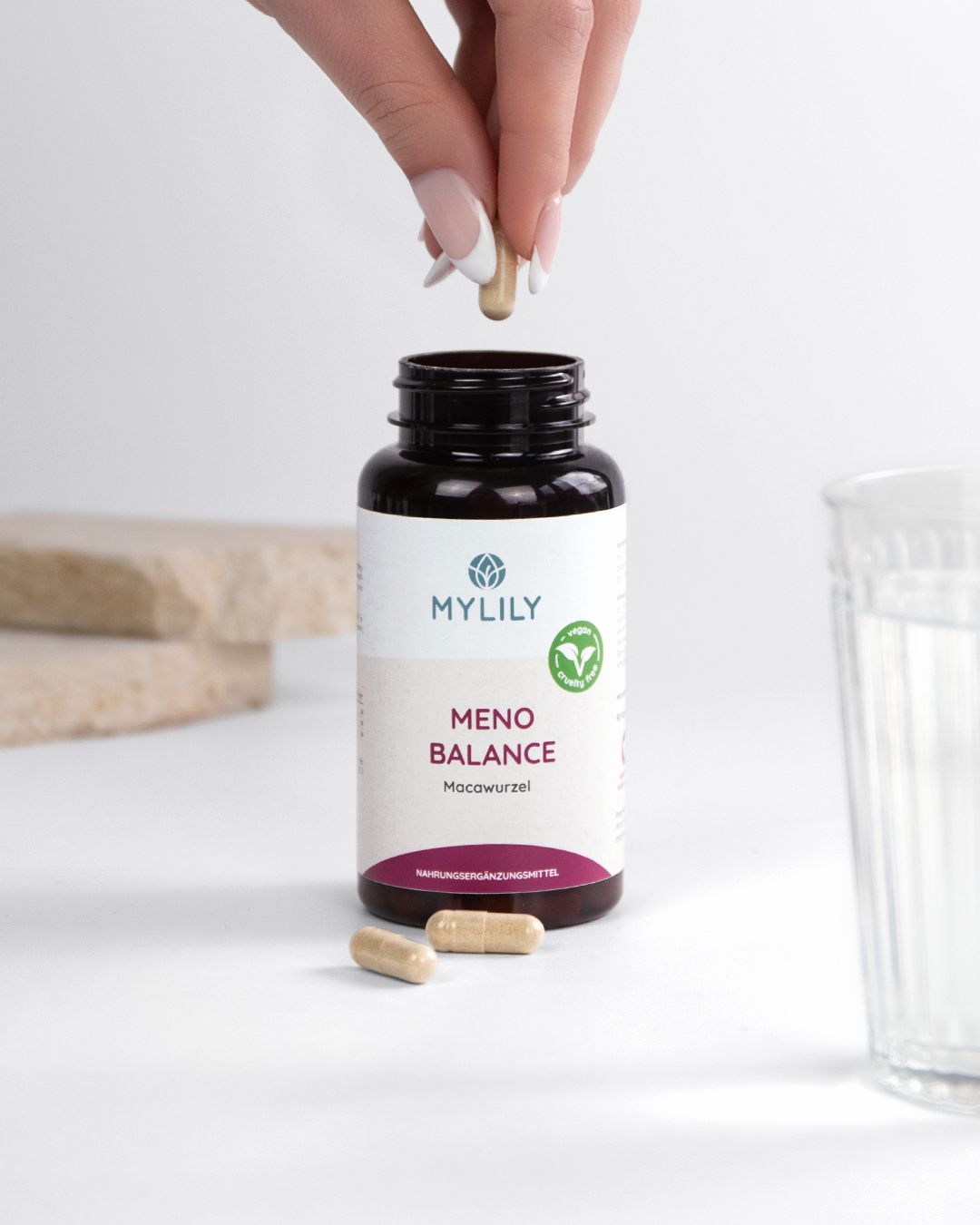 Bouteille brune avec des capsules Mylily Meno Balance. Une capsule est retirée.
