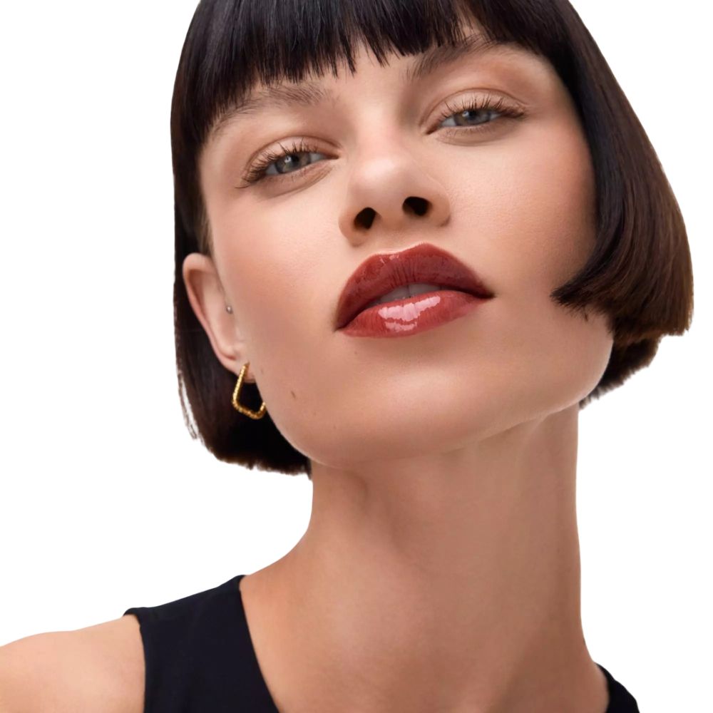 Close-up van een vrouw met glanzende, rode lippen. Kort, donker haar. Gouden oorbel.