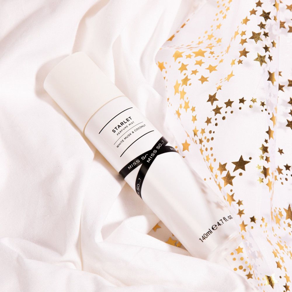 Brume parfumée blanche sur tissu blanc avec étoiles dorées. Texte: STARLET, White Musk & Coconut, MISS SO...?. 140ml.