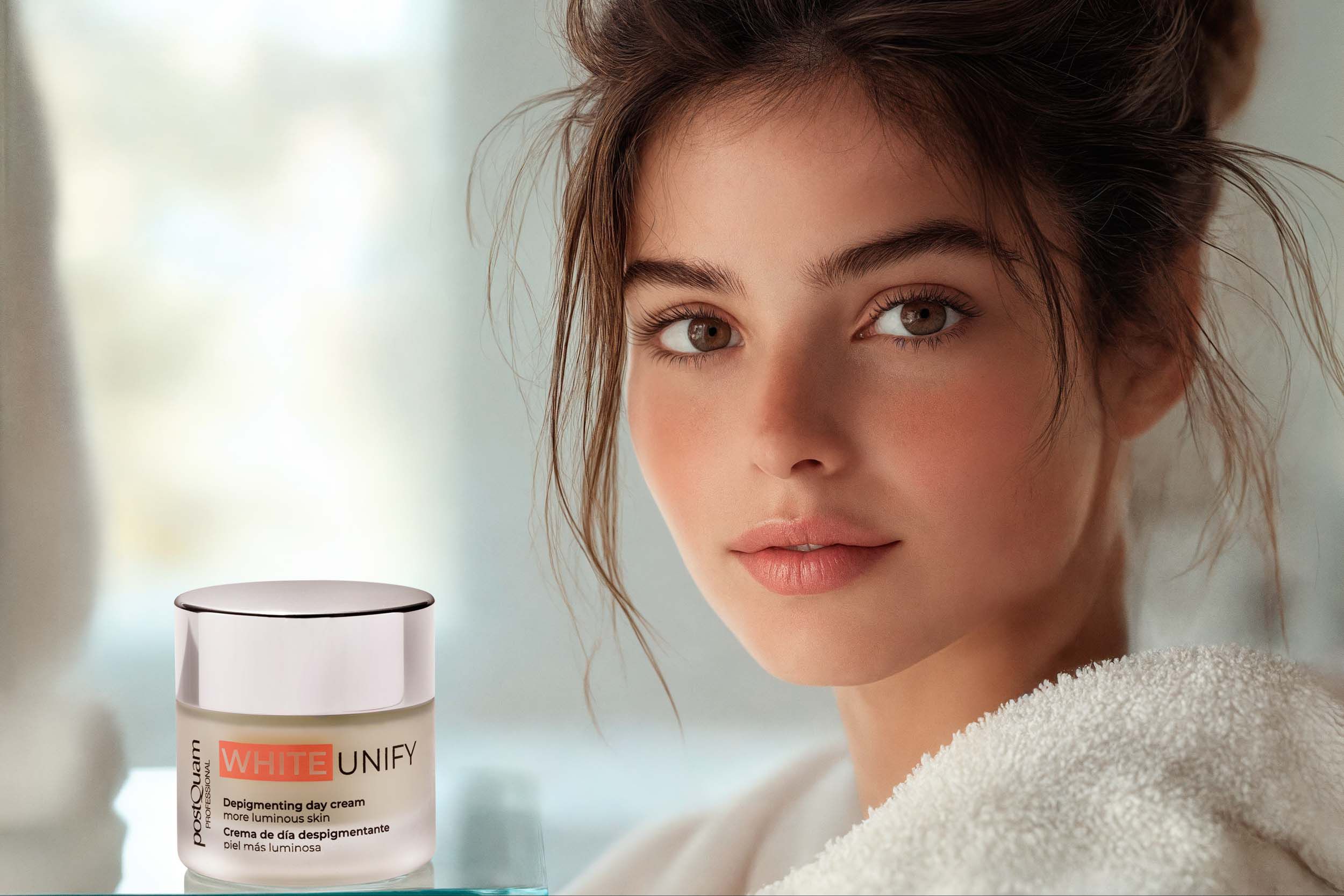 Vrouw met crèmepot. Opschrift WHITE UNIFY, Depigmenting day cream, meer stralende huid. Merk Postquam. Product ernaast.