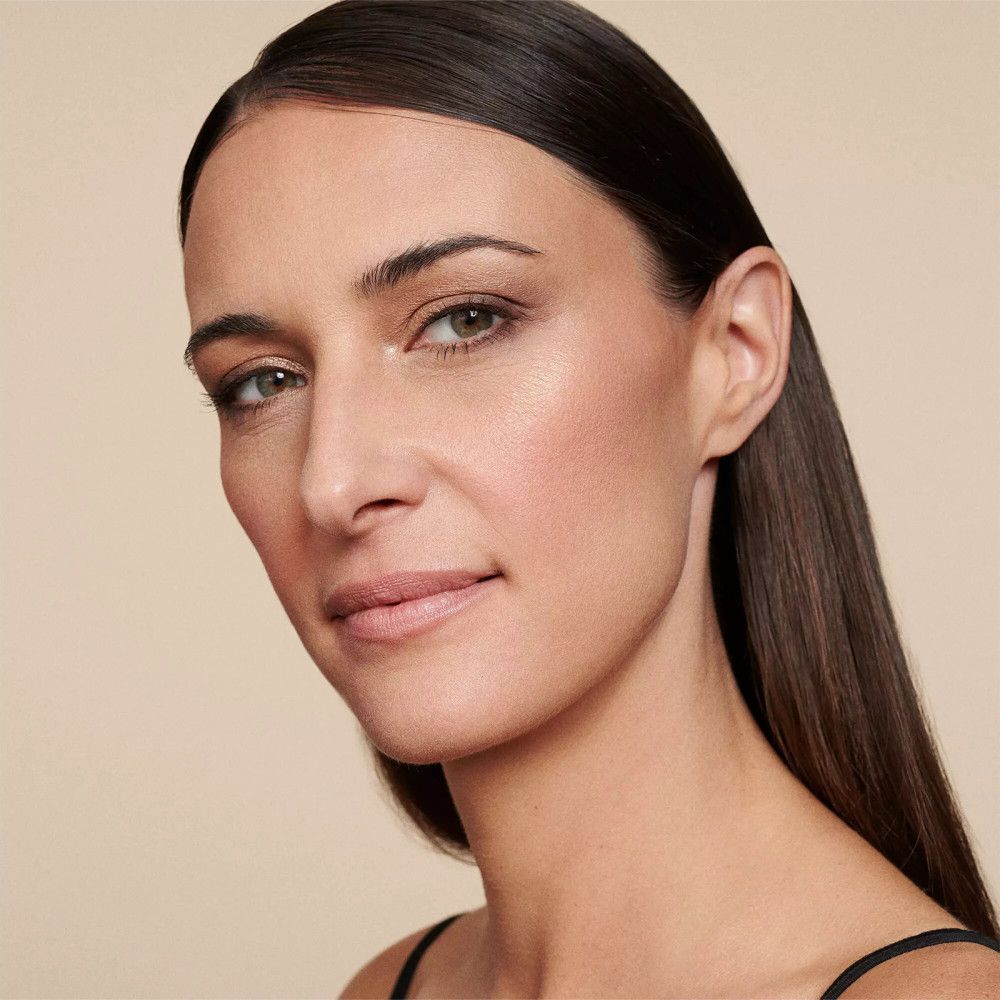 Close-up van een vrouw met make-up. Ze draagt nude oogschaduw en heeft een natuurlijke teint. Zwarte top.