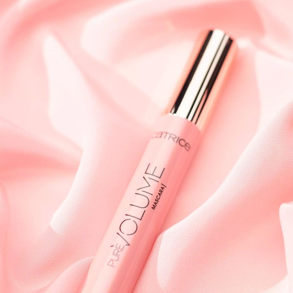 Roze mascara-tube met gouden dop. Op roze stof. Productnaam en merk zichtbaar.