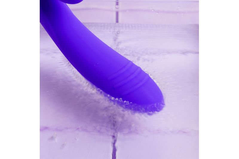 Paarse vibrator onder water. De punt van de vibrator is zichtbaar, omgeven door water. Water stroomt over het oppervlak.