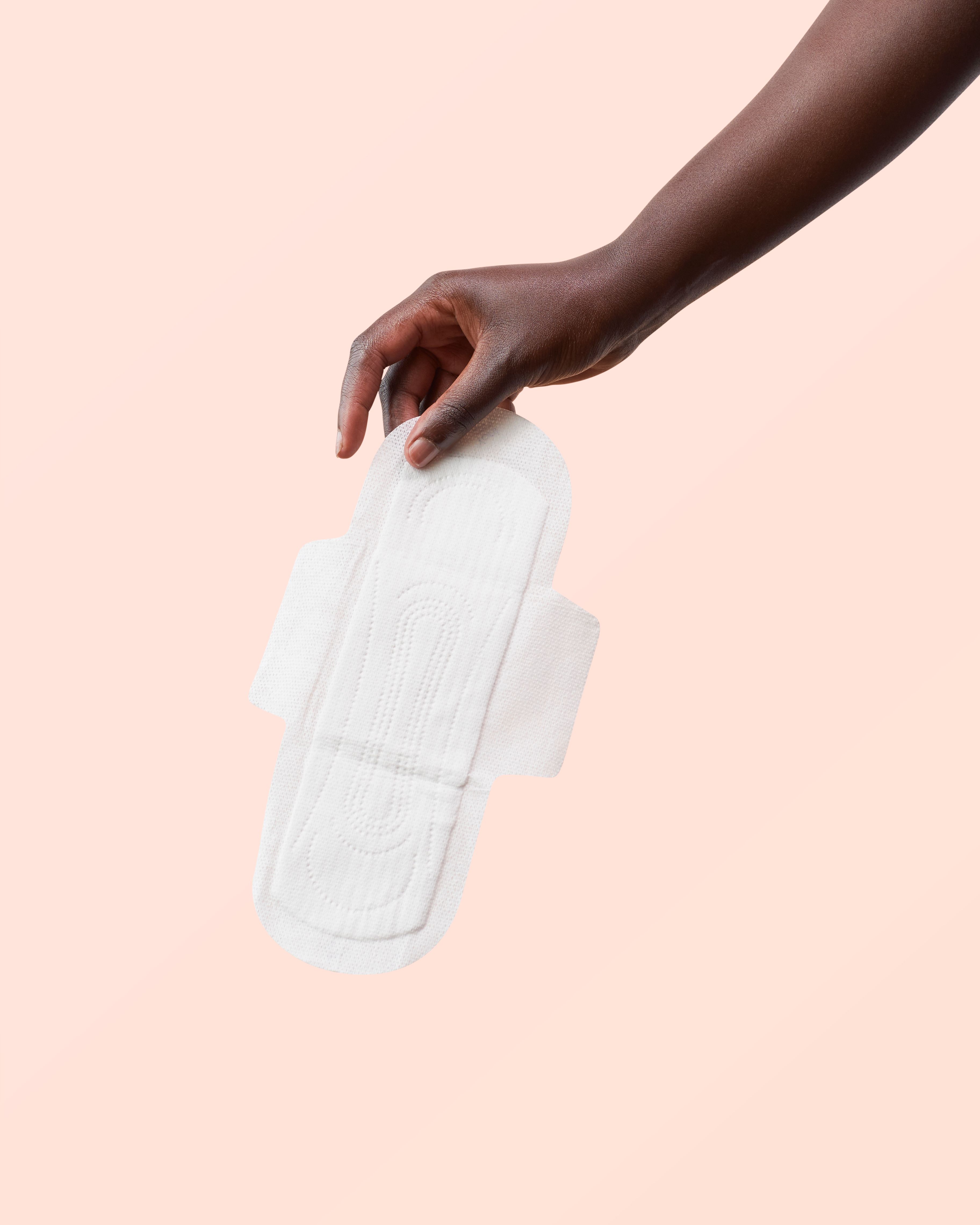 Een hand houdt een Yoni biologisch katoenen maandverband met vleugels vast.