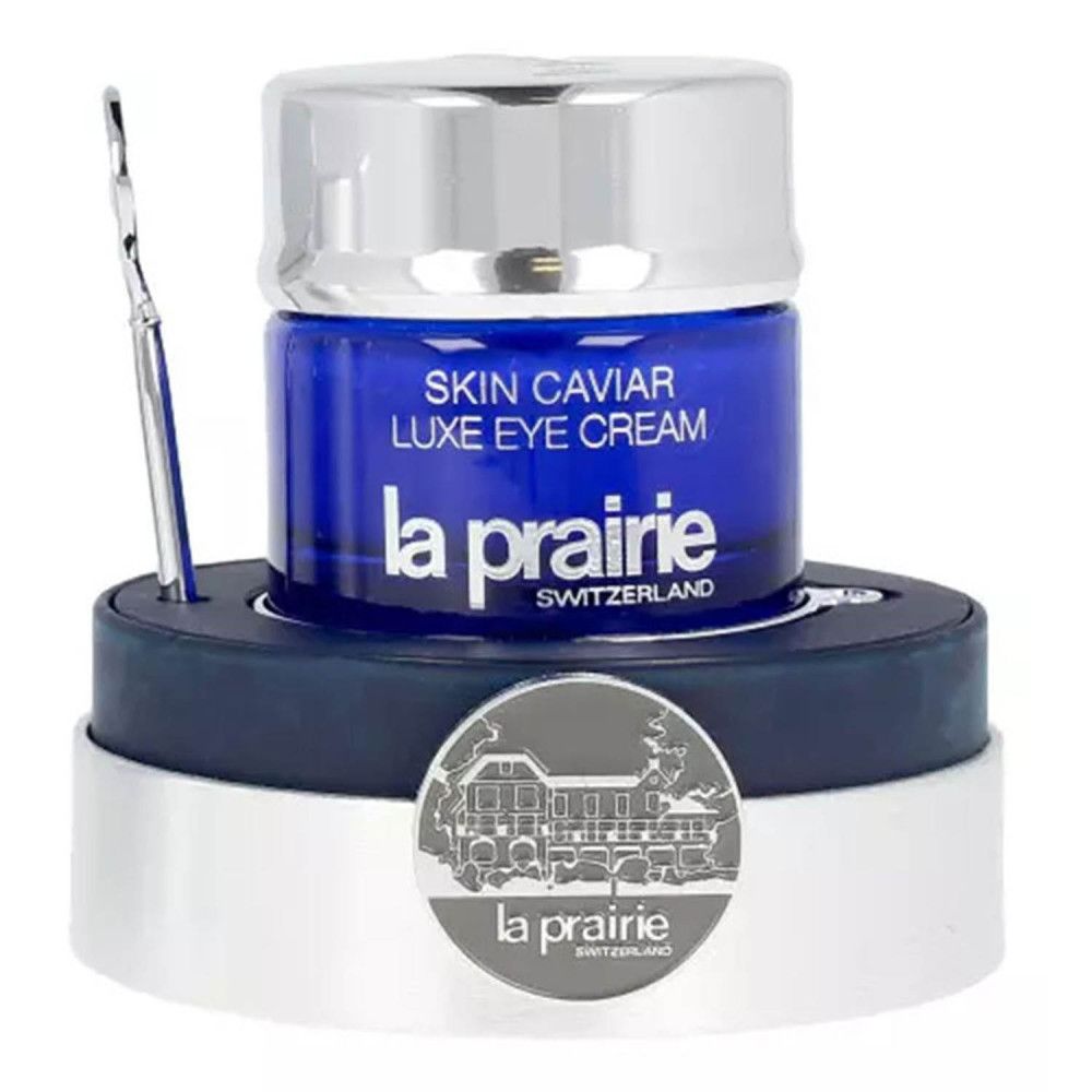 Blauwe pot met zilveren deksel, spatel en voet. Opschrift: Skin Caviar Luxe Eye Cream, La Prairie, Switzerland.