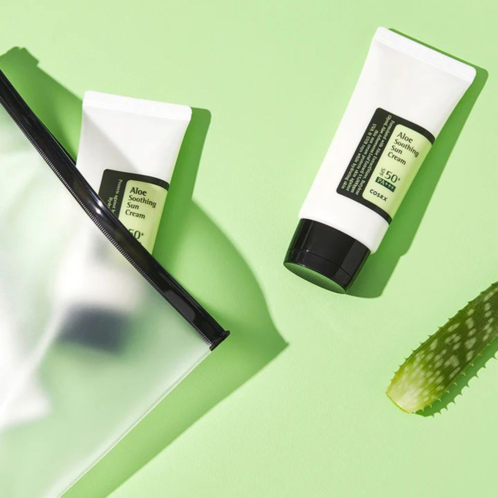 Twee tubes met zwarte dop en opschrift: Aloe Soothing Sun Cream, COSRX. Op groene achtergrond.