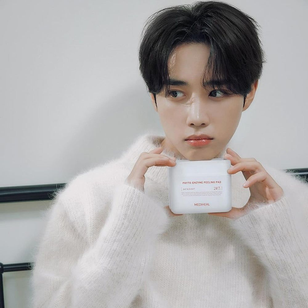 Une personne tient un contenant blanc avec "PHYTO-ENZYME PEELING PAD" et "MEDIHEAL".