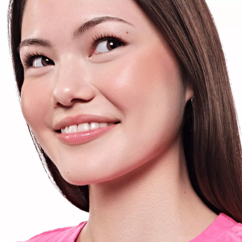 Portret van een vrouw met een gebruinde huid en blush op de wangen. Ze lacht en heeft lang donker haar.