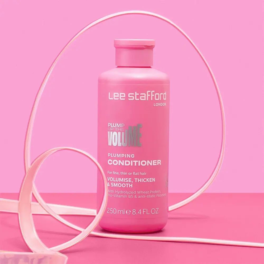 Roze fles LEE STAFFORD LONDON. Tekst "Plump Up The Volume" en "Conditioner". Decoratief lint op de achtergrond.