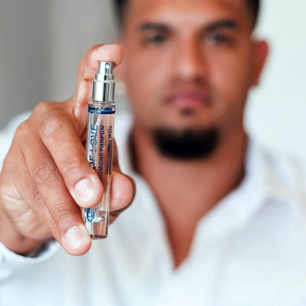 Un homme tient un flacon de spray phéromone "Eye of Love" pour hommes, sans parfum.