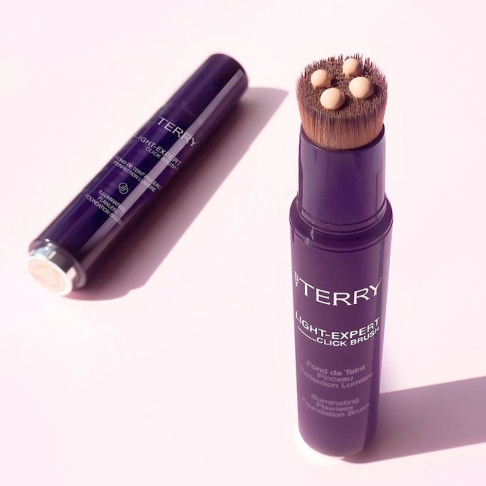 Deux applicateurs de fond de teint By Terry Light-Expert Click Brush. Un fermé, un avec pinceau et gouttes de fond de teint.
