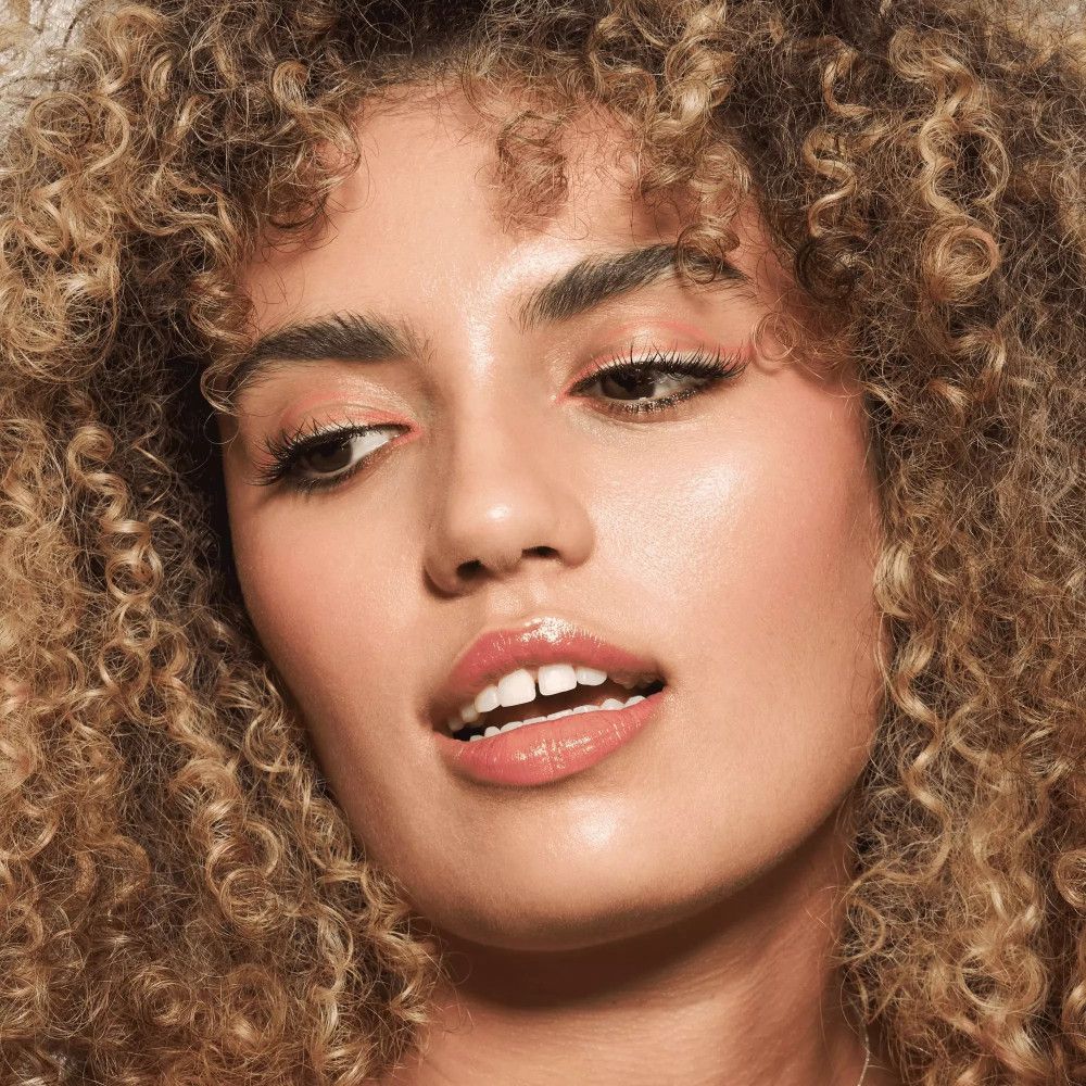 Femme aux cheveux bouclés avec maquillage. Crayon khôl sur la paupière supérieure.