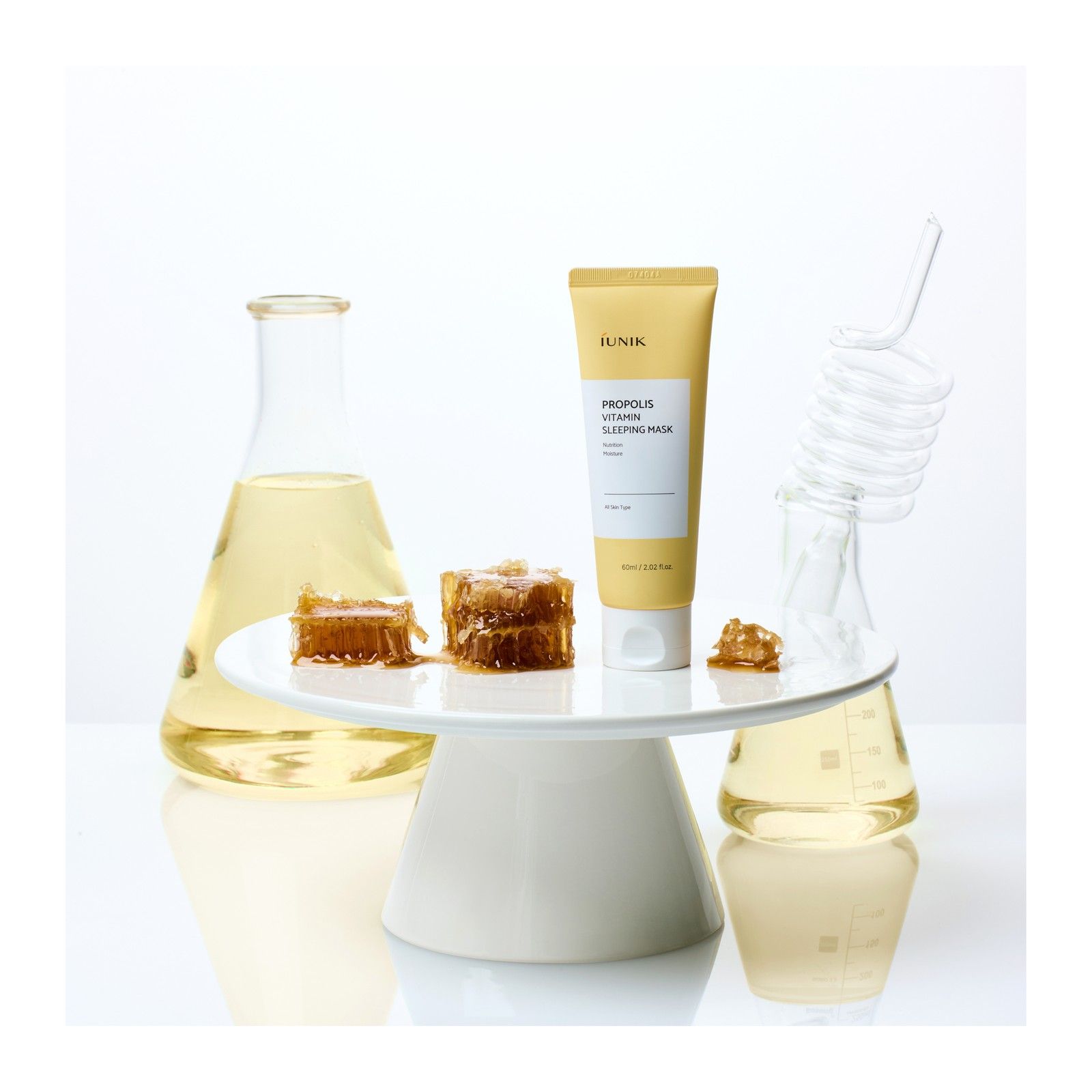 Tube de masque de nuit Propolis Vitamine iUNIK avec rayons de miel et flacons de laboratoire.