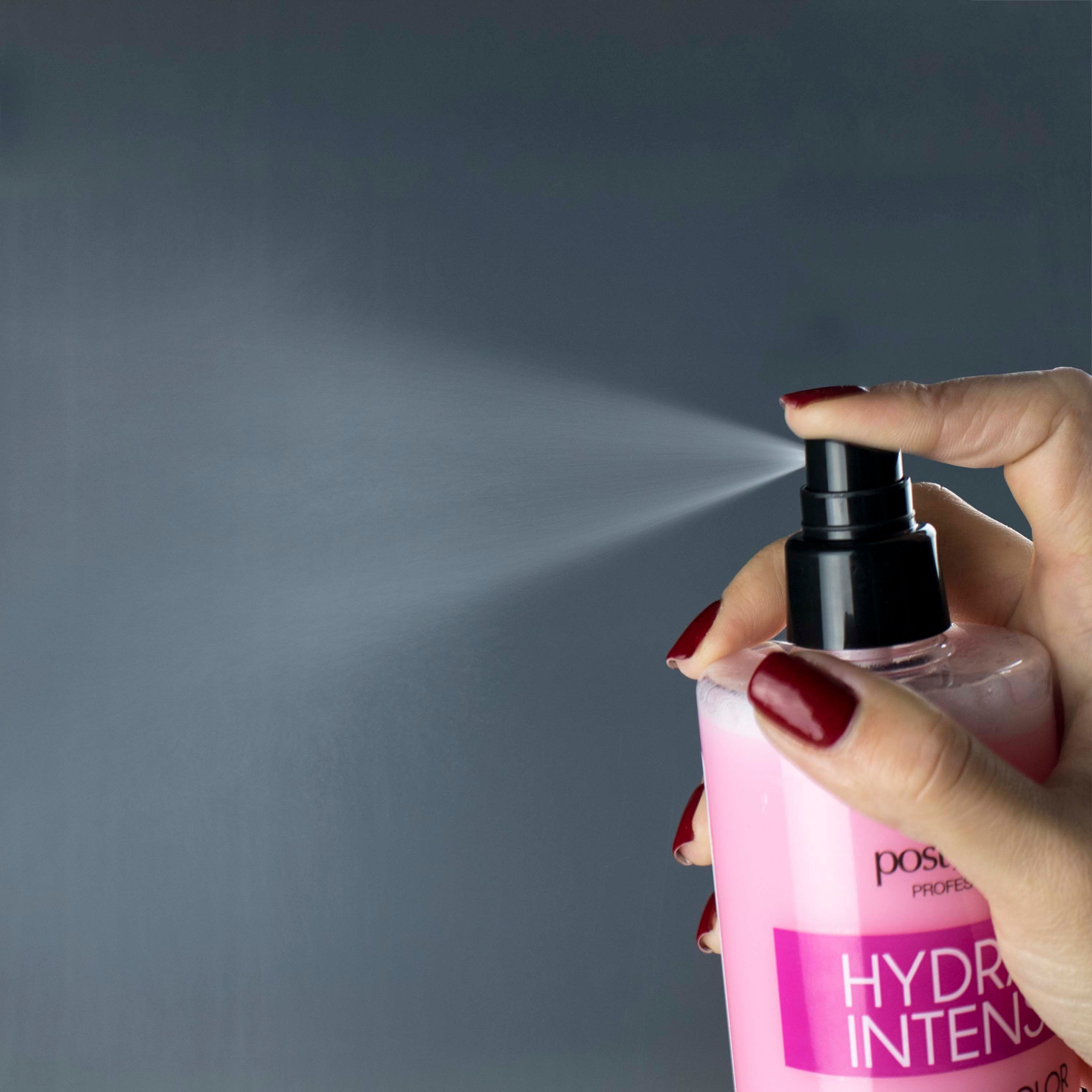 Hand spuit vloeistof uit een roze fles. Zwarte sproeikop. Rode nagellak.