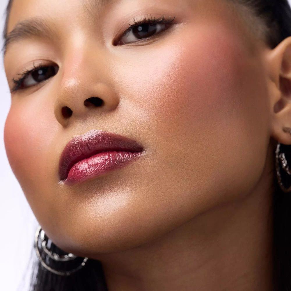 Close-up van een persoon met donkerrode lippen. De huid is gebruind. De lippen glanzen.