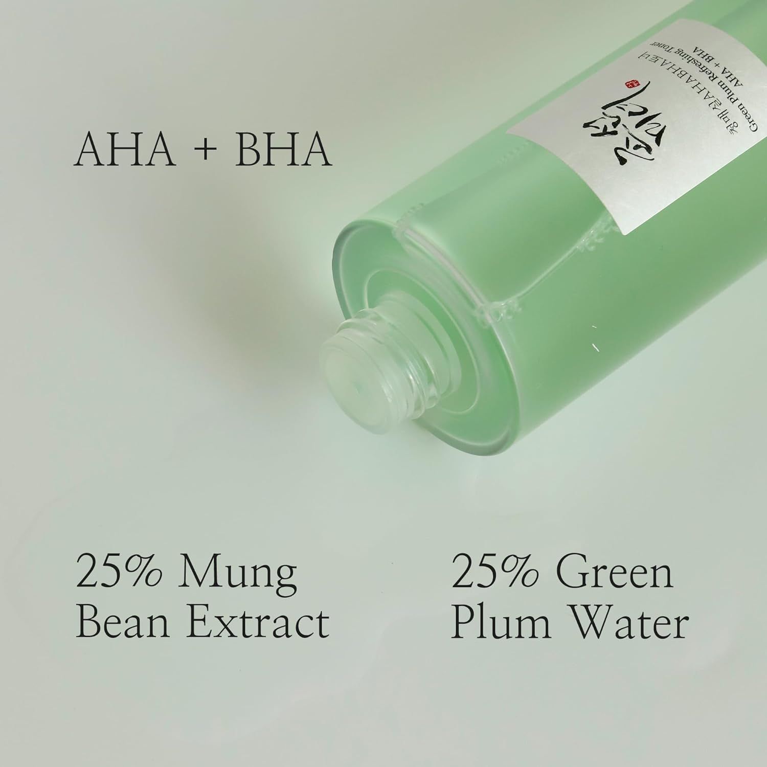 Productfles van onderaf gezien. Tekst: AHA + BHA, 25% mungboonextract, 25% pruimenwater. Transparante vloeistof.