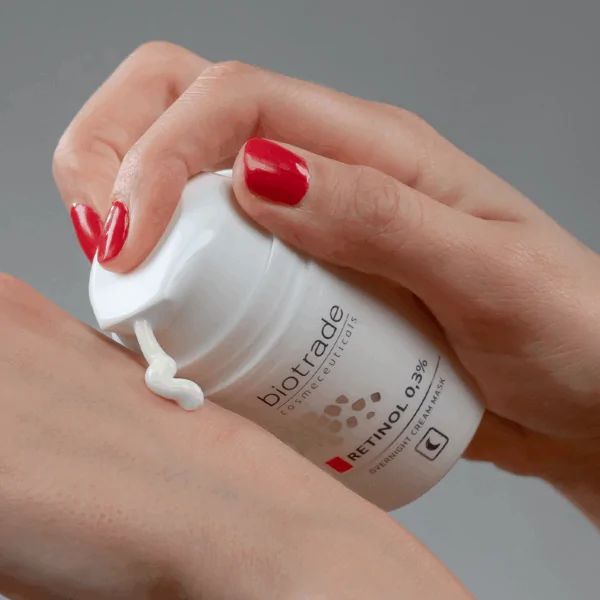 Flacon blanc Biotrade, Retinol 0,3% et masque de nuit. Crème appliquée sur la peau.