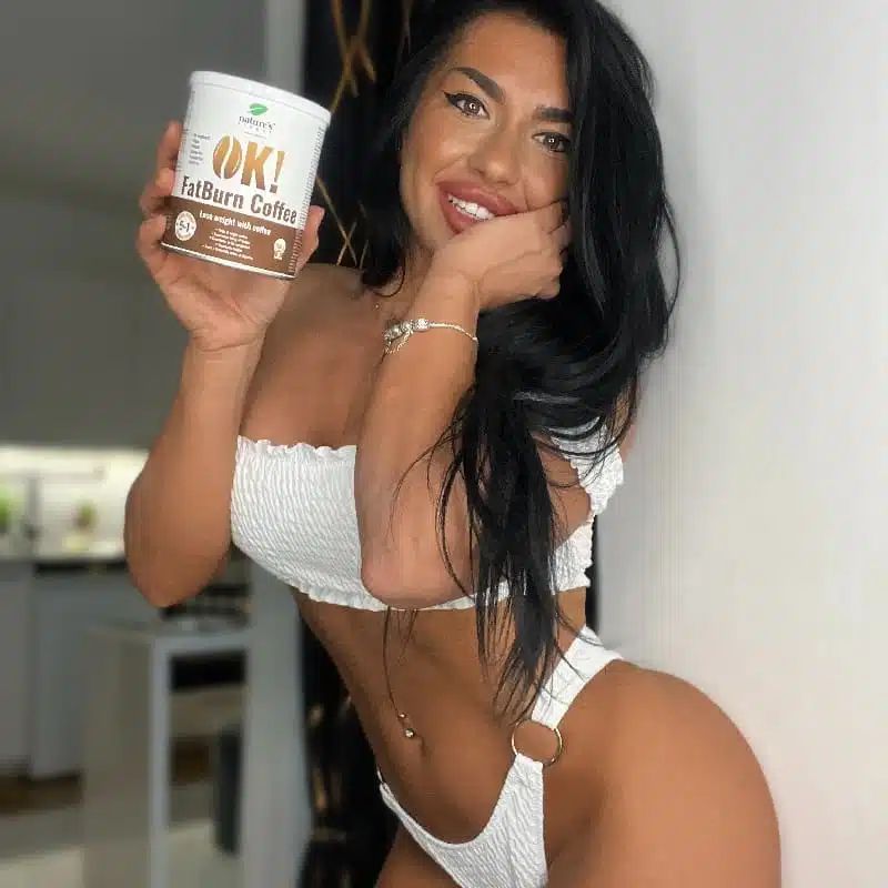 Une femme tient une boîte OK! FatBurn Coffee, souriant à la caméra.