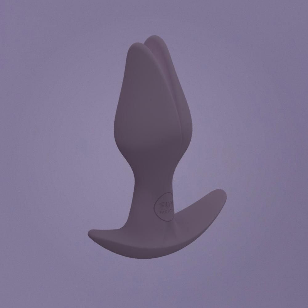 Bouchon anal gris foncé en forme de fleur, tenu dans une main.
