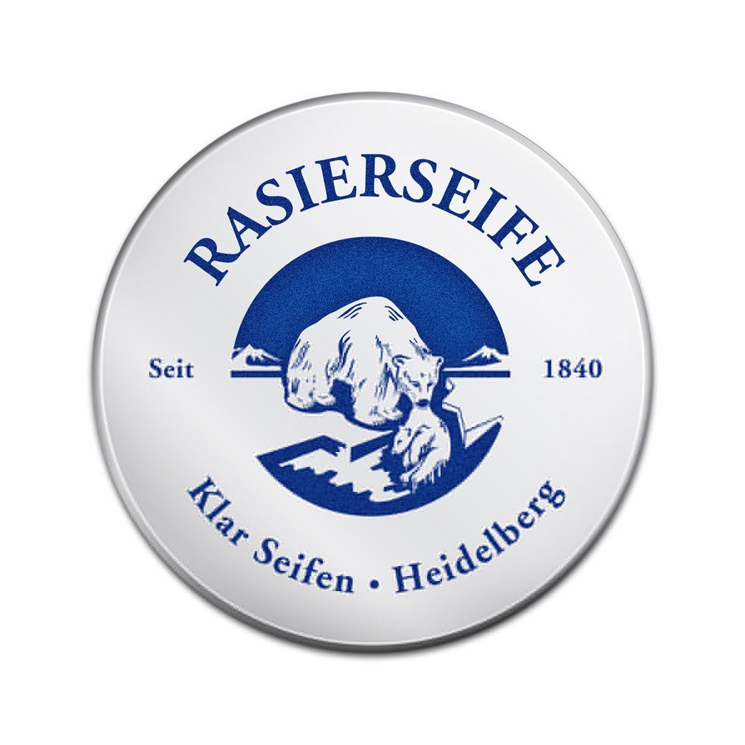 Ronde deksel van een scheerzeepdoos. Logo en tekst: Rasierseife, Klar Seifen, Heidelberg. Metalen rand, witte achtergrond.
