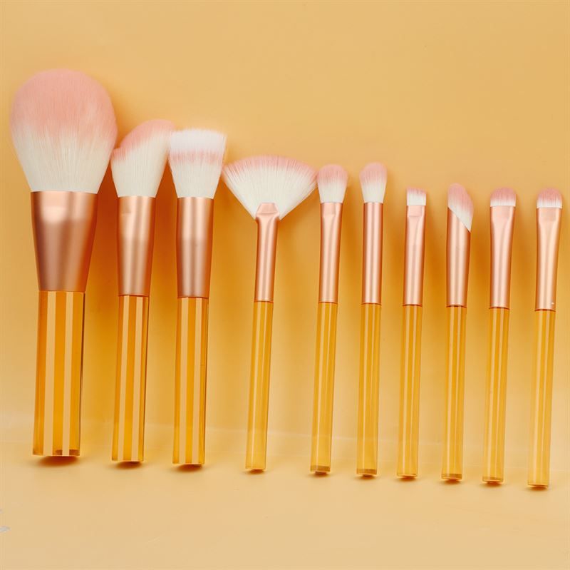 Ensemble de pinceaux de maquillage avec manches orange transparents et poils roses. Différentes formes et tailles.