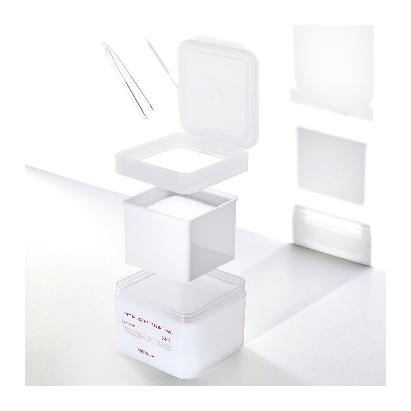 Een gedemonteerde container met peeling pads, met een pincet.