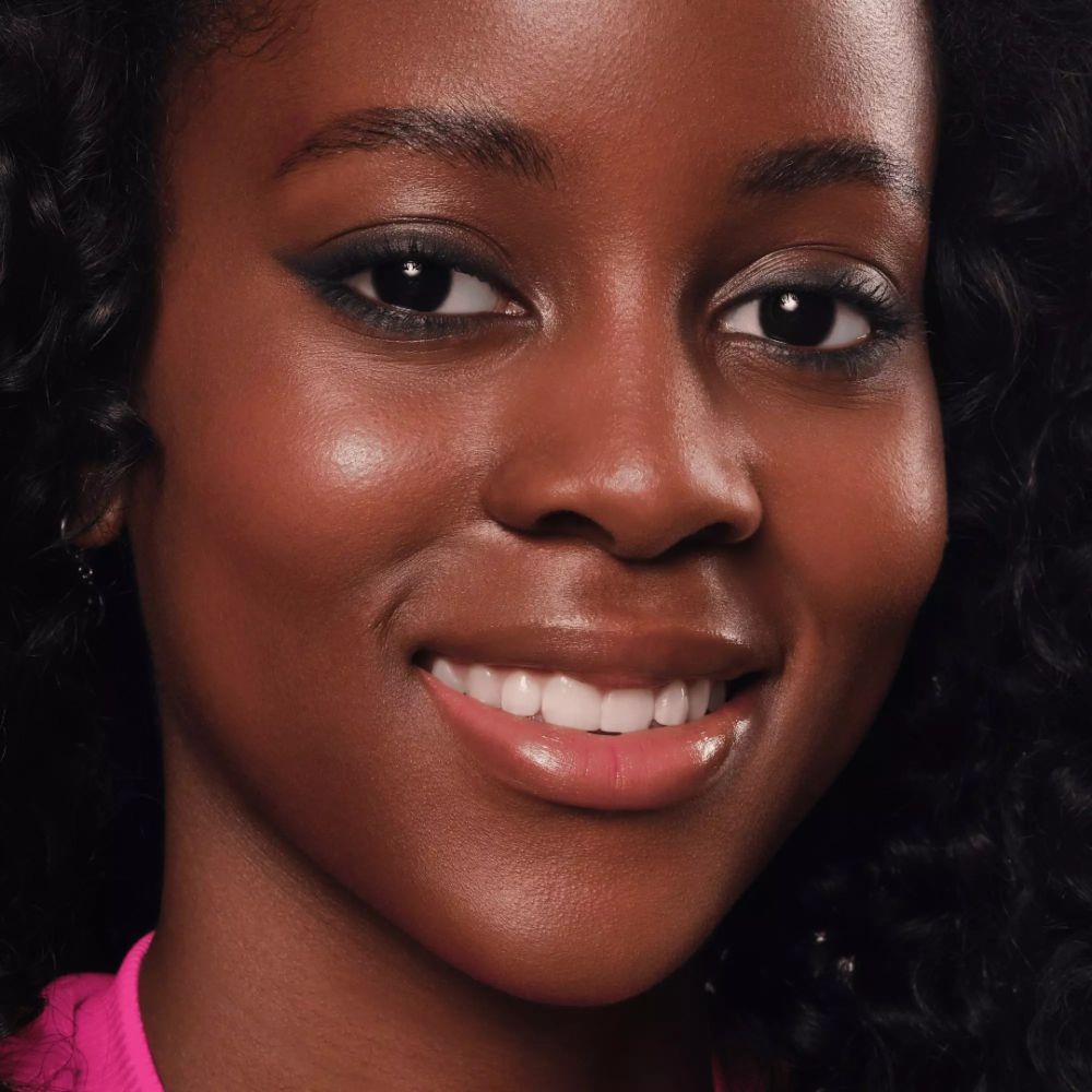 Gros plan d'un visage avec eyeliner. Peau foncée, yeux foncés, sourcils dessinés.