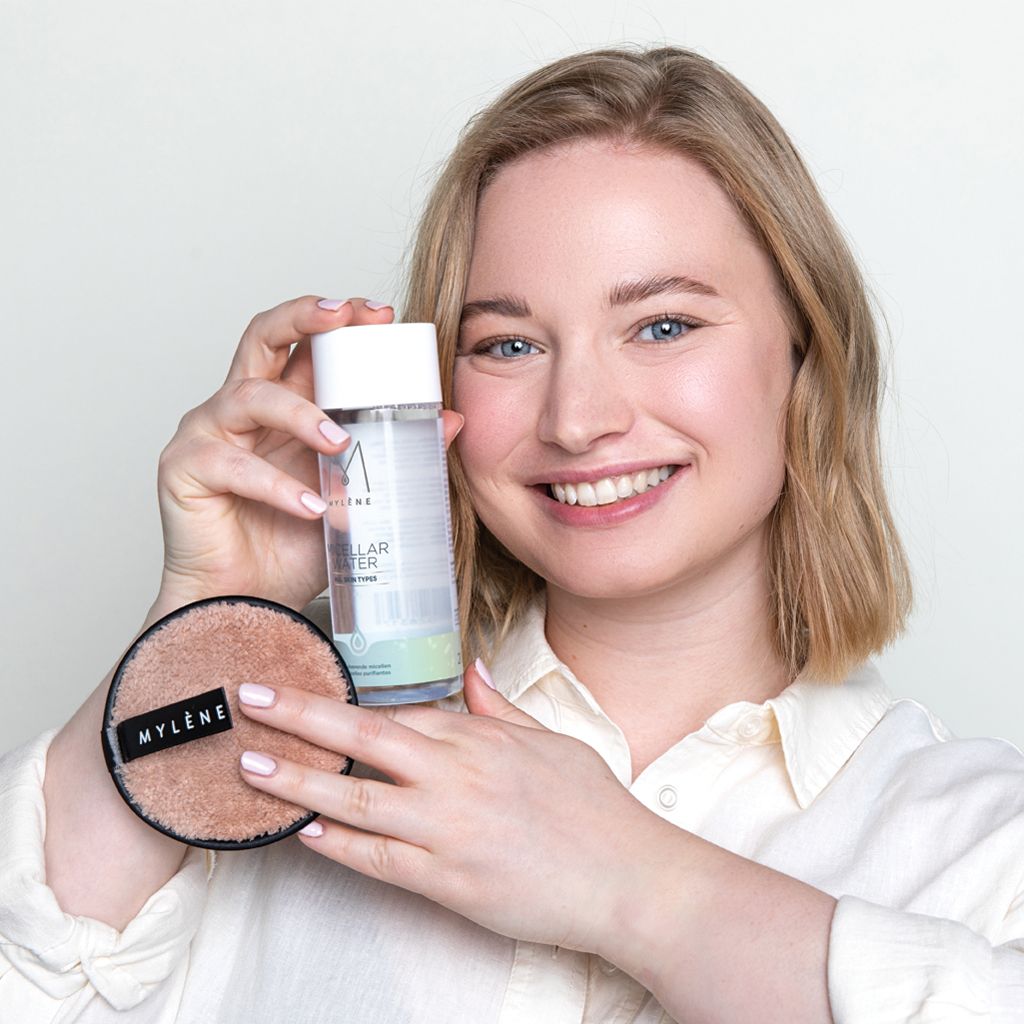 Femme tenant une bouteille d'eau micellaire Mylène et un disque de nettoyage rond.