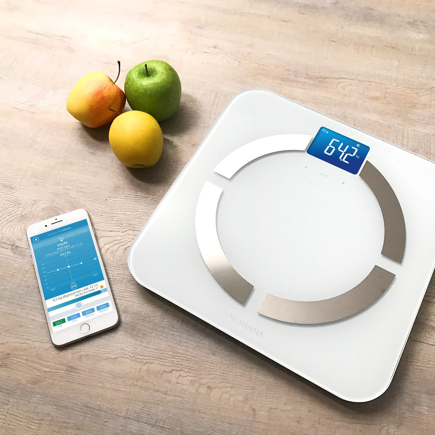 Balance d'analyse corporelle, smartphone et fruits sur surface en bois. Balance avec affichage.