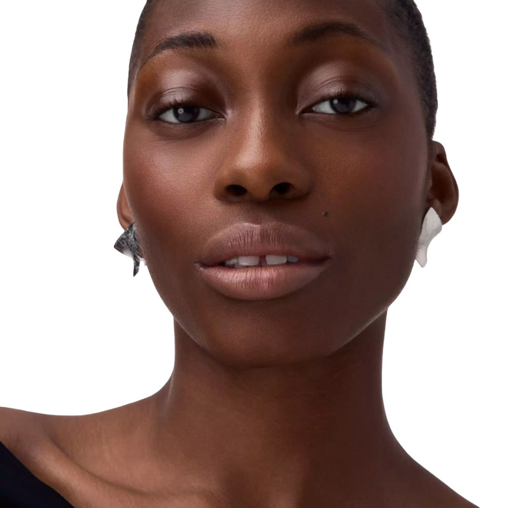 Portrait d'une femme portant du rouge à lèvres. Boucles d'oreilles. Teint et couleur des lèvres visibles. Lumière naturelle.