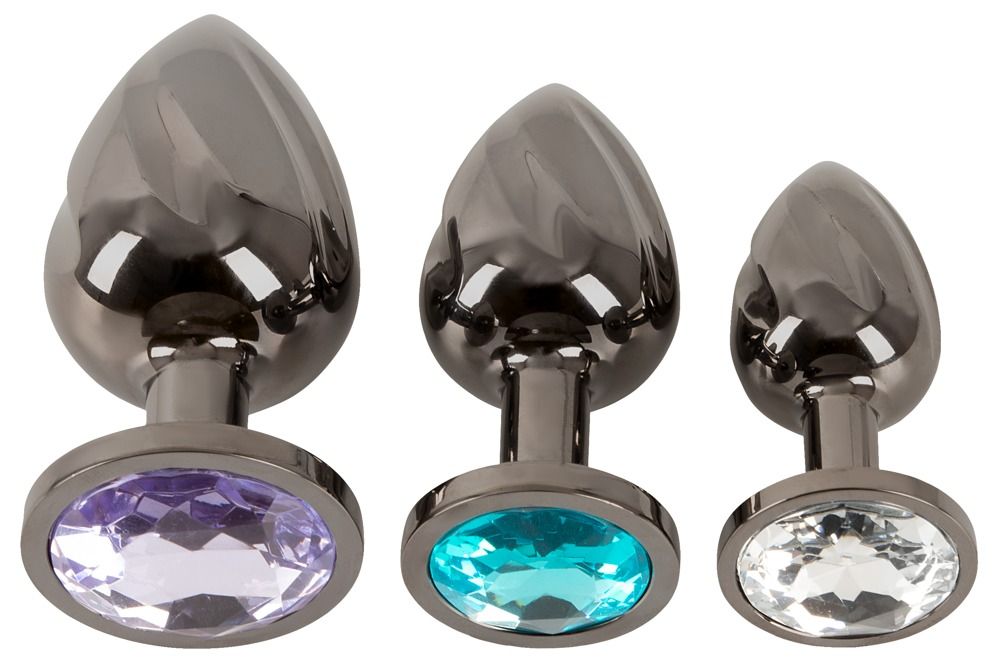 Trois plugs anaux en métal à surface torsadée avec différentes pierres précieuses.