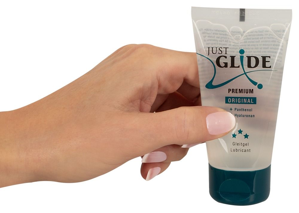 Main tenant un tube transparent avec bouchon bleu. Inscription : JUST GLIDE PREMIUM ORIGINAL. Lubrifiant médical.
