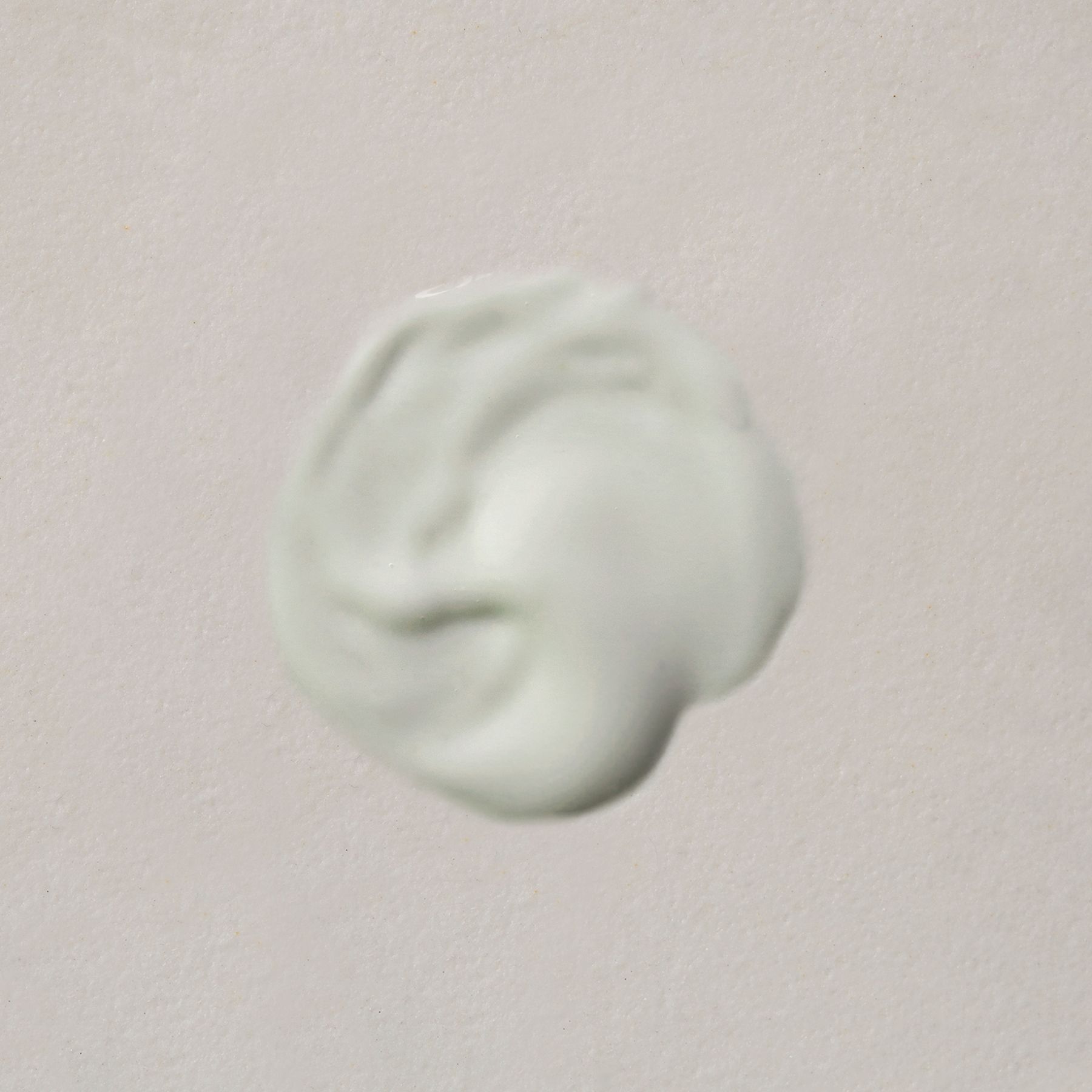 Une touche de masque facial vert clair sur fond clair.