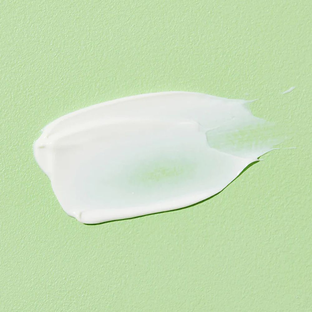 Vlek witte crème op groene achtergrond. Textuur zichtbaar.