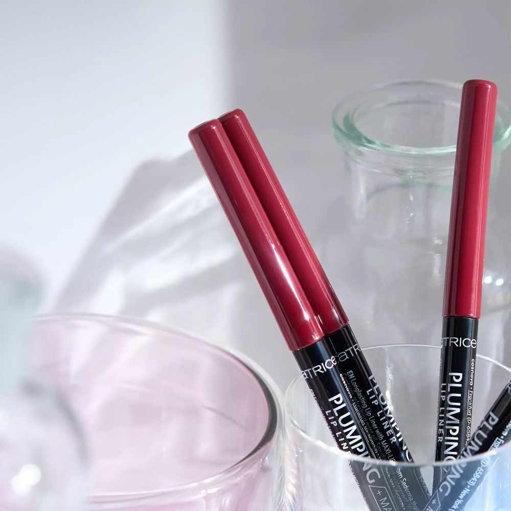 Twee lipliners in een glas. Rood, cilindrisch. Zwarte tekst: PLUMPING LIP LINER / MAXI-LIP. Merk: Catrice.