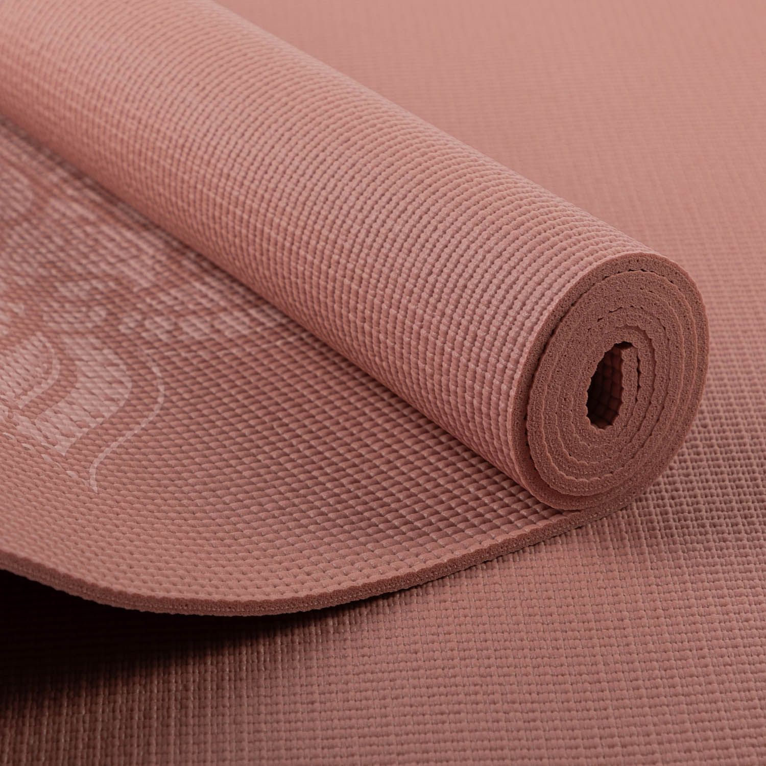 Opgerolde roze yogamat. Gegeribbelde oppervlakte. Wit logo en patroon. Detail van de opgerolde rand.