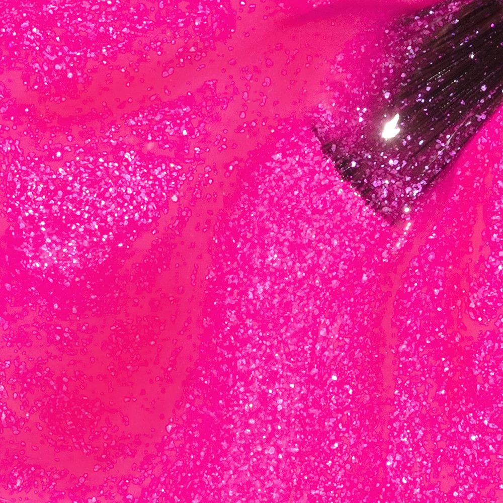 Roze nagellak met glitter. De kwast is gedeeltelijk zichtbaar.