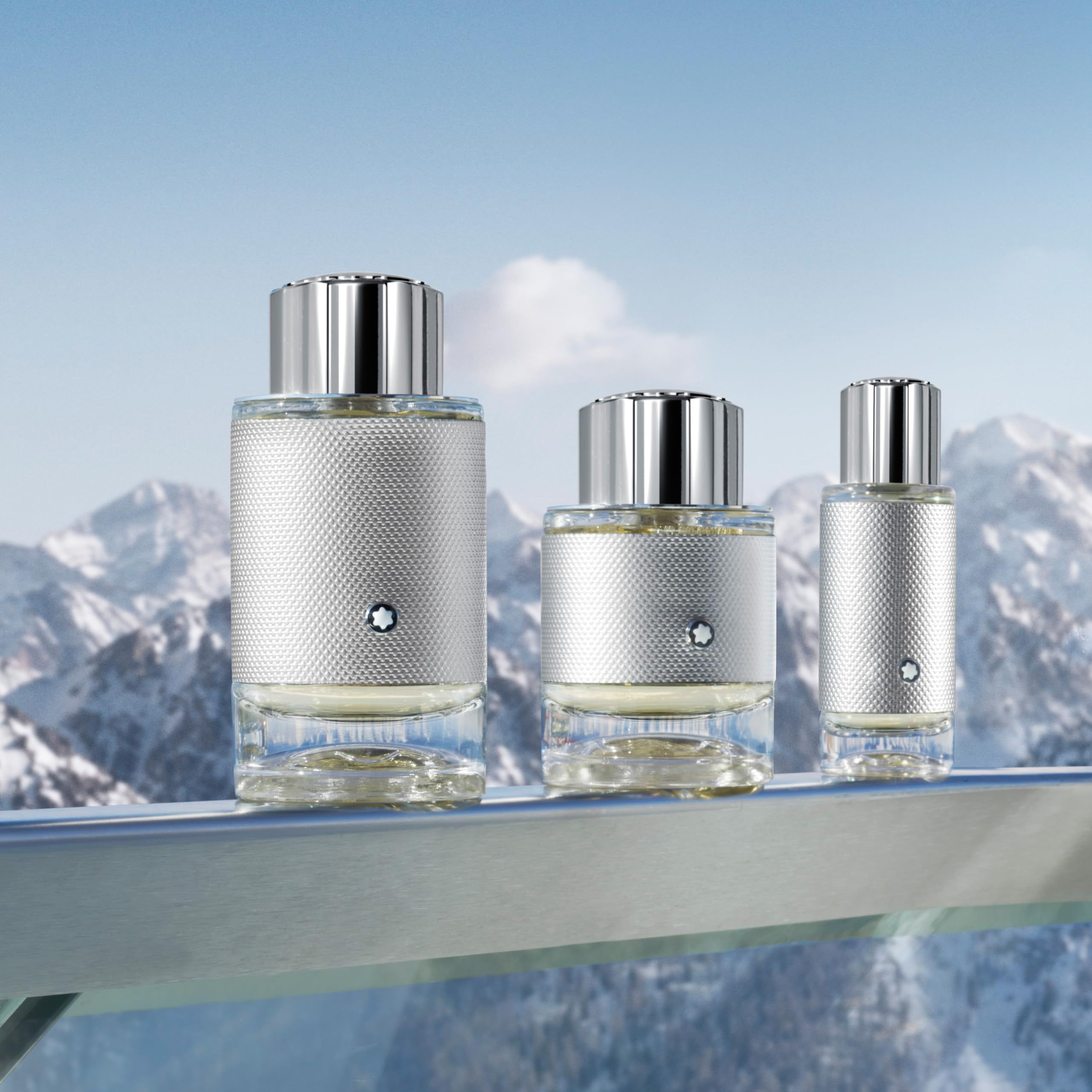 Drie Montblanc Explorer Platinum EdP Nat. Spray flacons. Zilverkleurig ontwerp, verschillende maten. Bergen op de achtergrond.