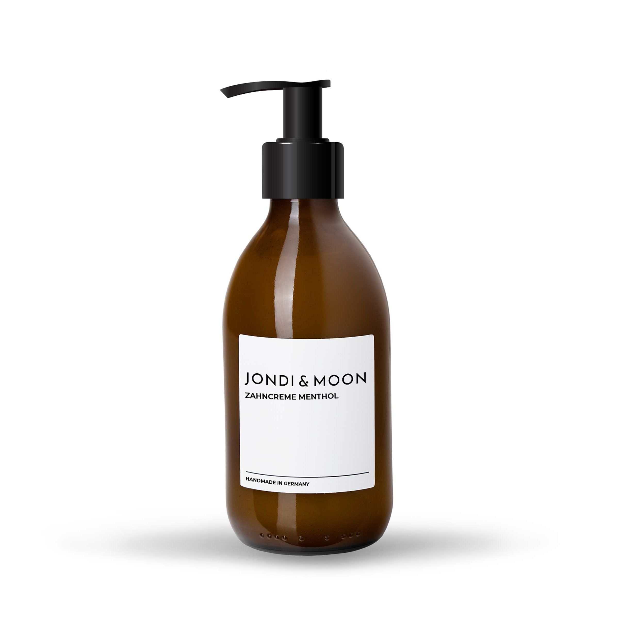 Flacon en verre brun avec pompe noire. Étiquette blanche avec texte: JONDI & MOON, Zahncreme Menthol. "Handmade in Germany".