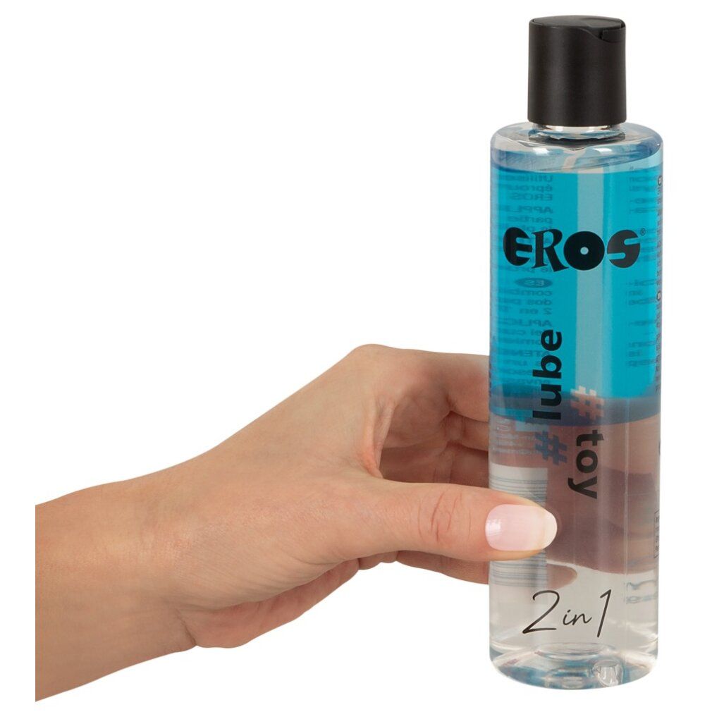 Main tenant une bouteille de lubrifiant EROS 2en1 et liquide pour jouets, bouchon noir.