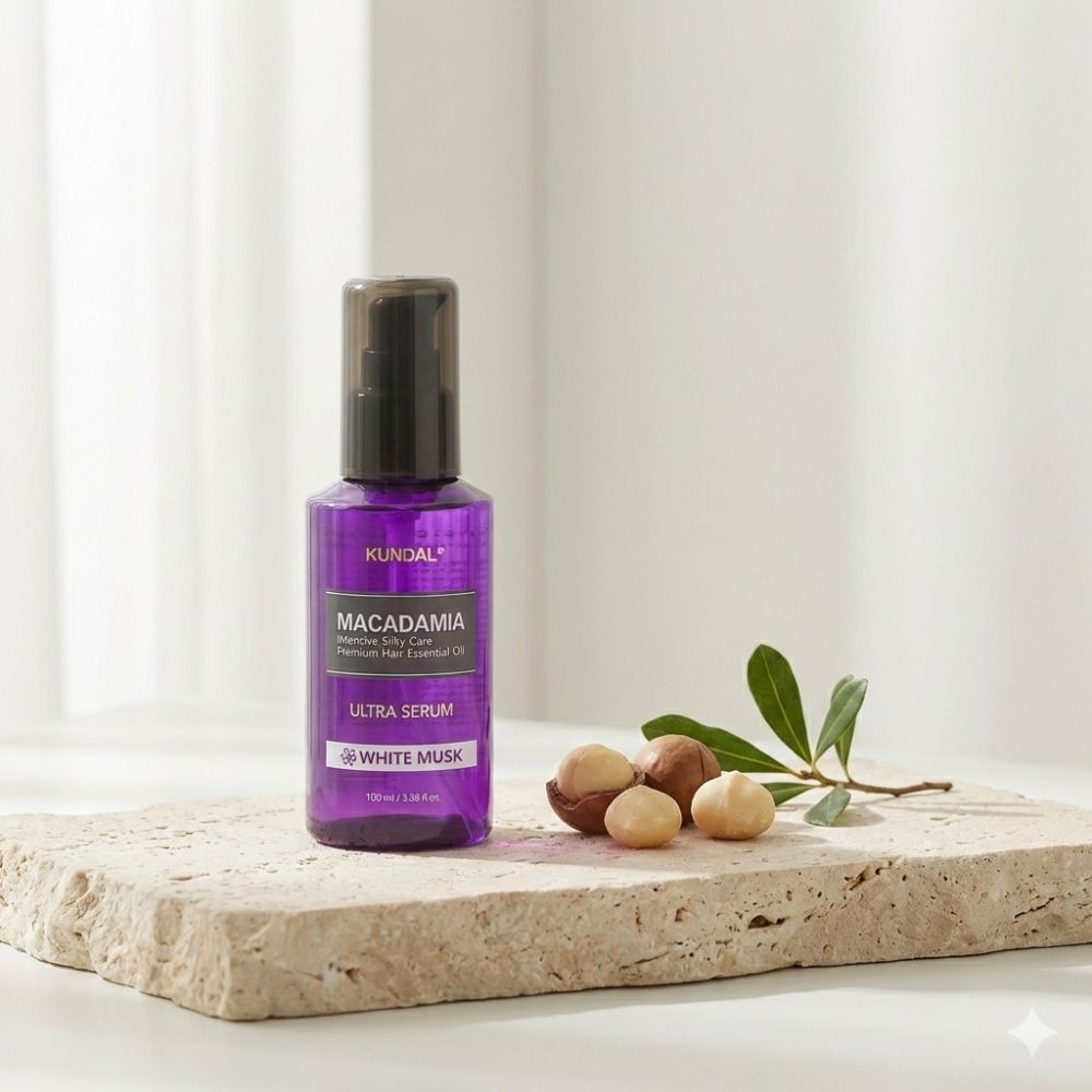 KUNDAL Macadamia Ultra Hair Serum White Musk dans un flacon violet sur une pierre avec des noix de macadamia.